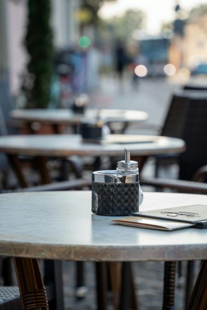 mehrere kleine Restaurant-Tische, die draußen stehen als Symbol für die einen Bewirtungsbeleg, den man als Reisekosten absetzen kann.